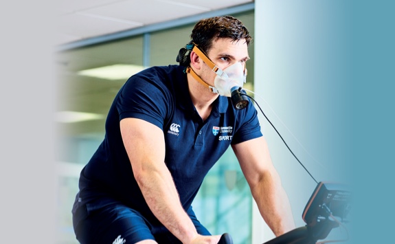 A person on an exercise bike with monitoring equipment